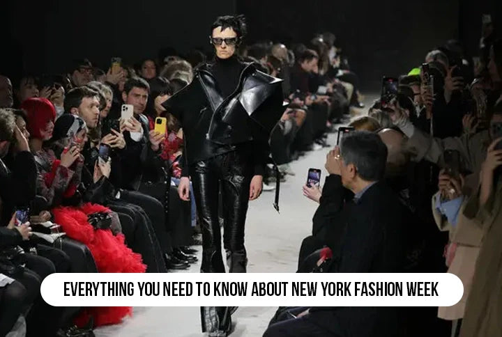 Runway model in black leather outfit walking at New York Fashion Week with audience capturing photos